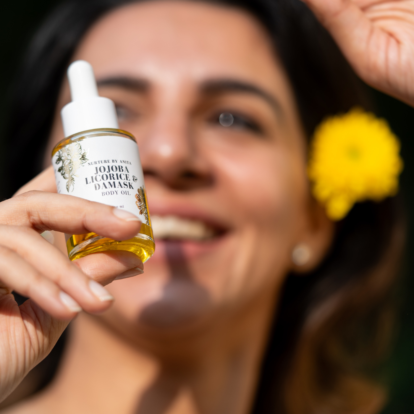 Girl holding body oil bottle happy - jojoba body oil - nurture by anita